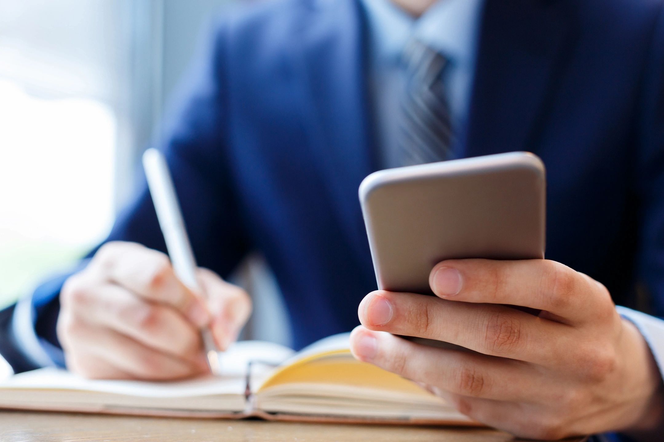 Person holding phone and taking notes